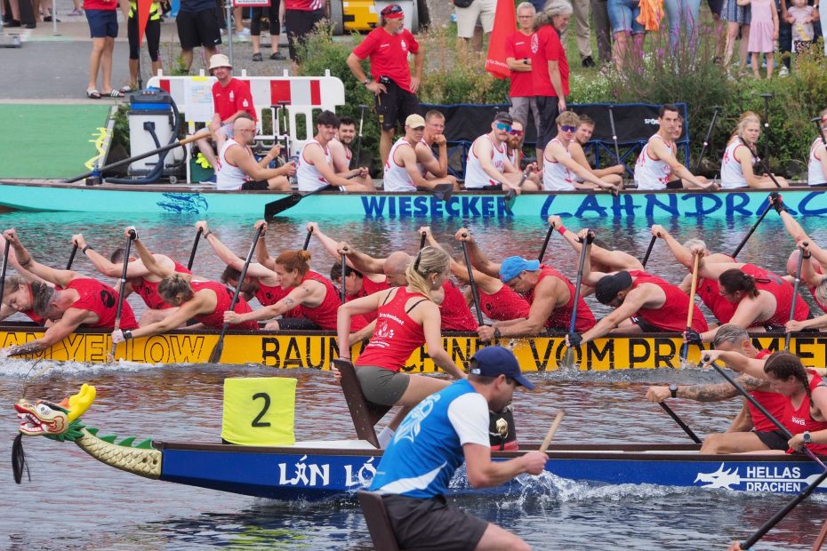 Drei Drachenboote beim Schlusssprint dicht nebeneinander, im Hintergrund Zuschauende