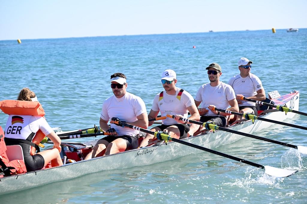 Vier Ruderer in einem Ruderboot. Die Steuerfrau trägt eine Schwimmweste.
