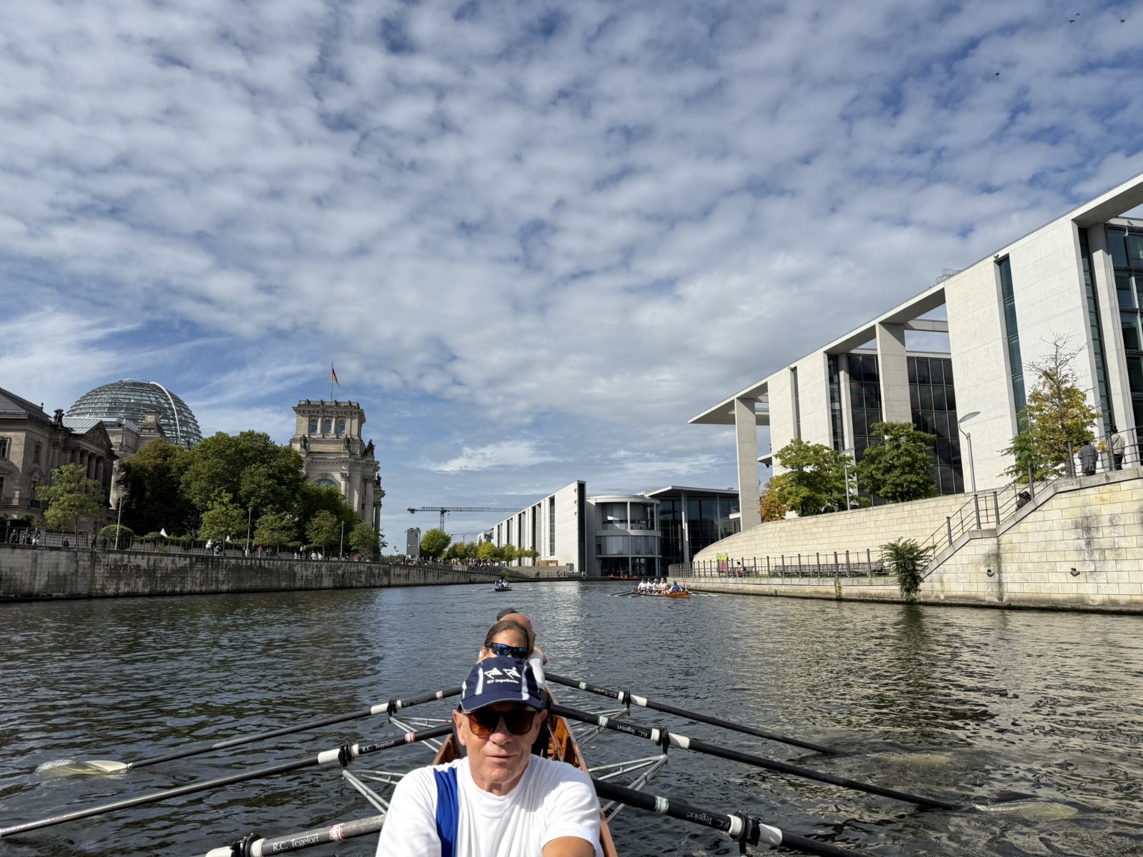 Im Vordergrund die Besatzung eines Gig-Vierers auf der Spree, im Hintergrund das Reichstagsgebäude und das Marie-Elisabeth-Lüders-Haus