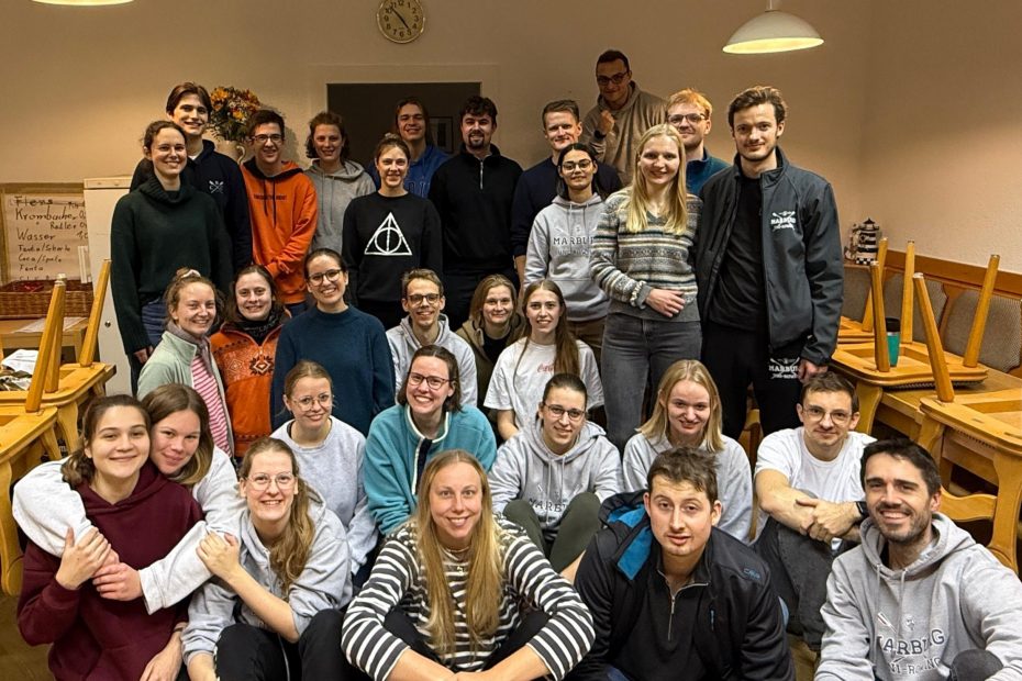 Eine Gruppe junger Menschen, einige sitzen im Vordergrund, andere stehen dahinter