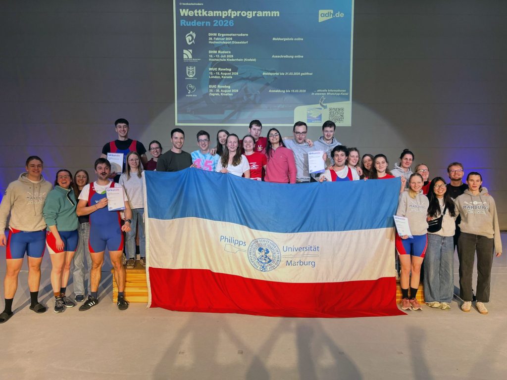Mannschaftsbild der Hochschulrudergruppe mit einer Flagge der Uni Marburg