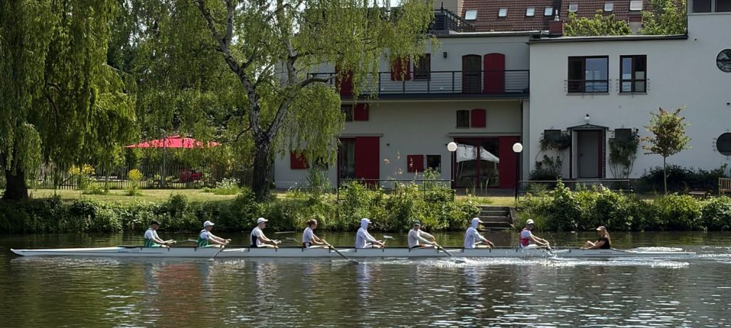 Ein Ruderachter auf der Lahn vor einem Haus im Bauhaus-Stil