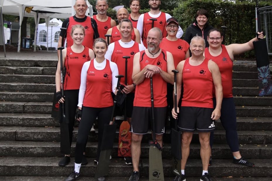 Die Mitglieder des Drachenbootteams stehen stolz und lachend auf einer Treppe